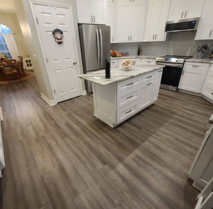 Modern kitchen with white cabinets, stainless steel appliances, and a central island with granite countertop.