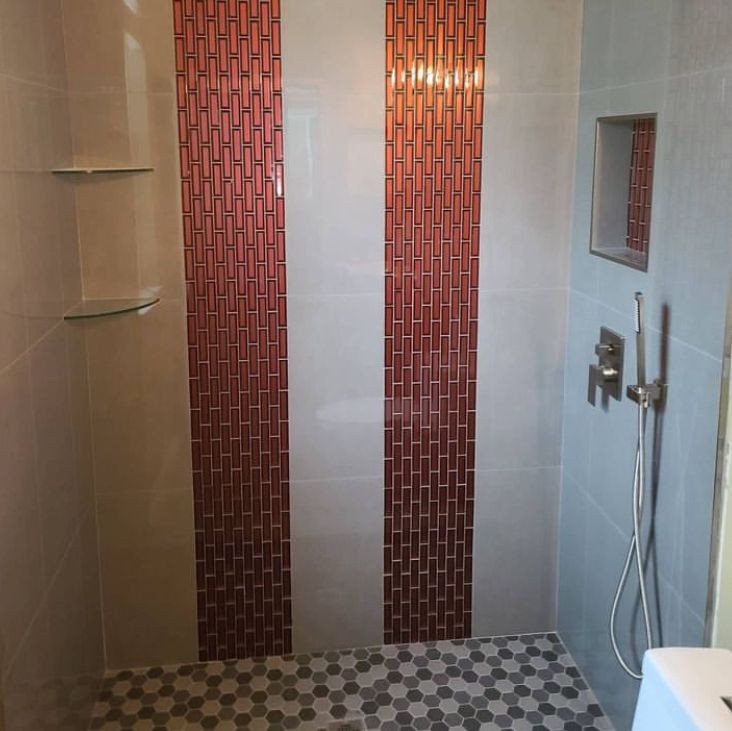 Modern shower with red vertical tile strips and hexagonal floor tiles.