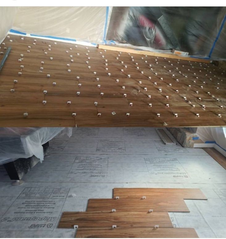 Laying wooden floor tiles with spacers on a prepared surface in a room under renovation.