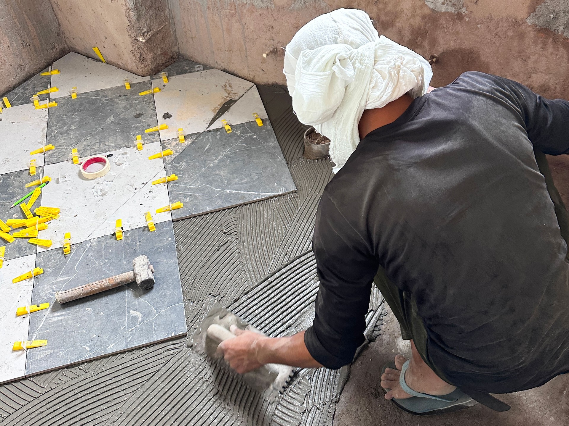 Image of modern bathroom floor renovation / laying grey and white marble diamond pattern tiles for contemporary home improvement